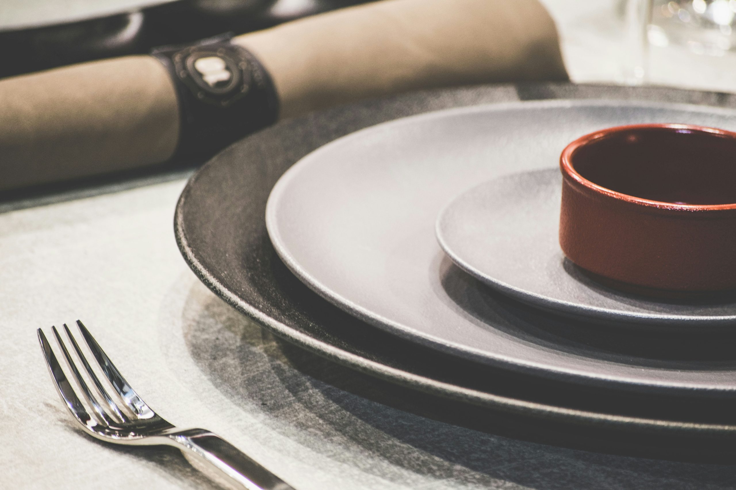 Photograph of a place setting at a table with plates and a fork