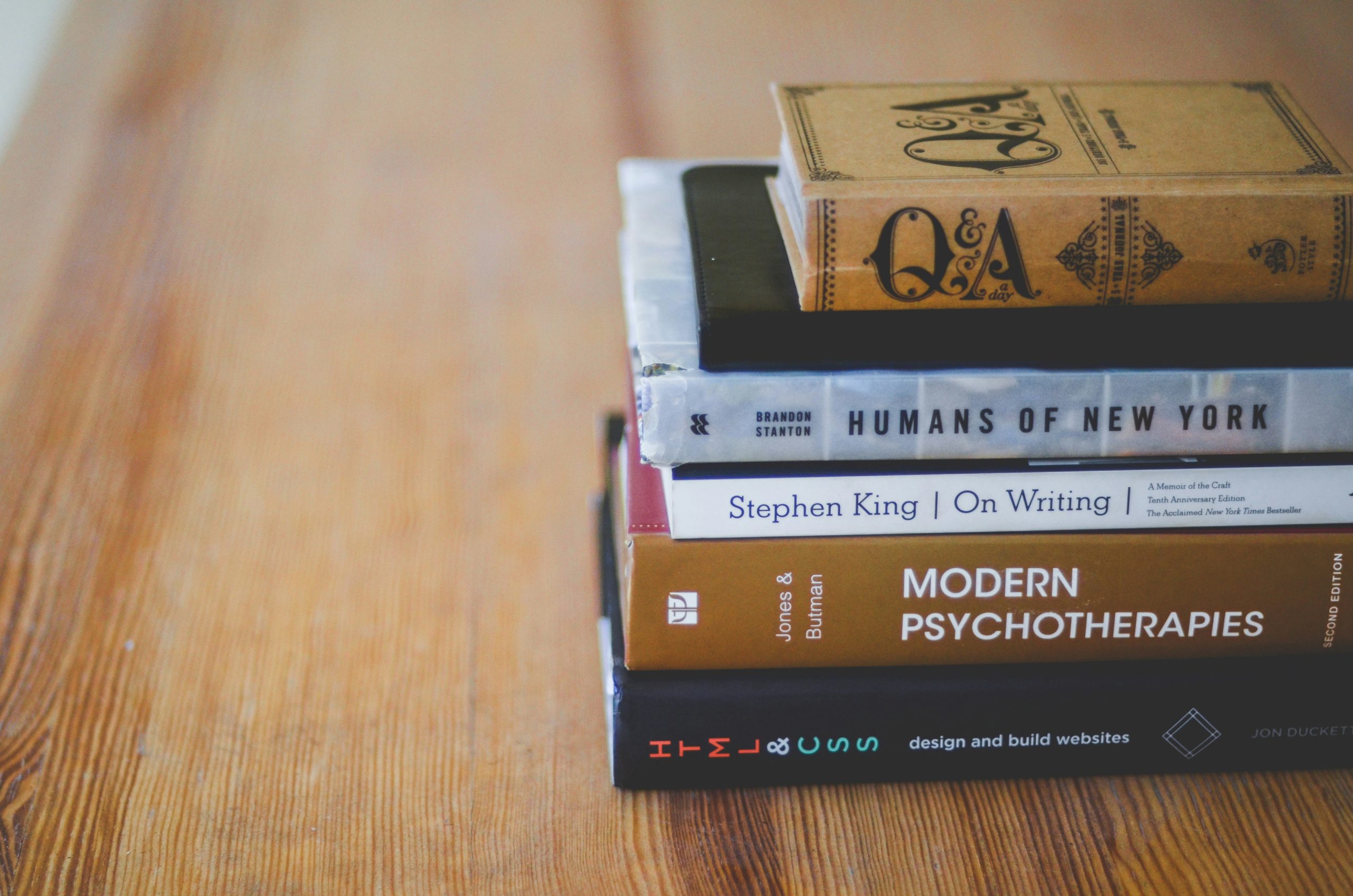 Photograph of six stacked books on a wooden surface