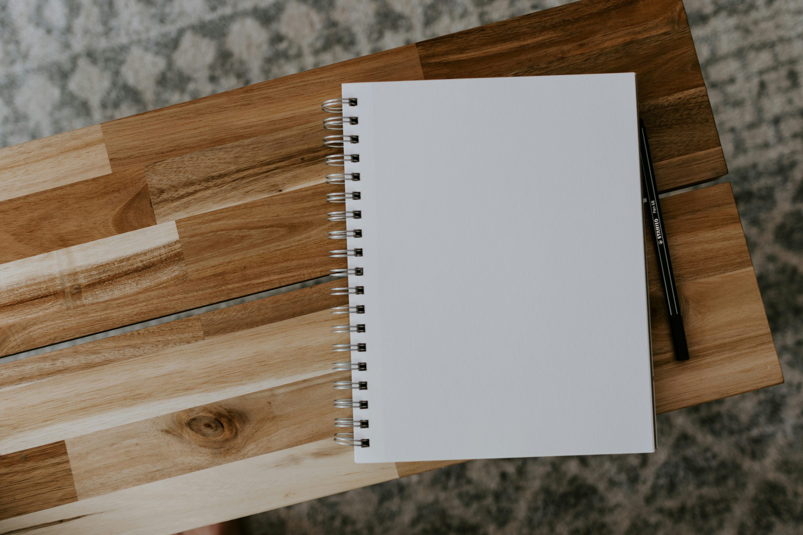 Photograph of a blank notebook and pen on a wooden bench